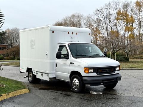 A 2007 Ford E-350 van with a white box cargo area parked at an angle on a street