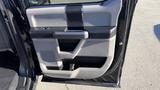 Interior door panel of a 2016 Ford F-150 featuring a black and gray design with a handle and storage compartment