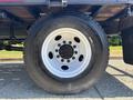Close-up of a 2004 Ford F-750 tire featuring a white rim with multiple spoke holes and a rugged black tire tread