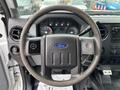 The interior view of a 2013 Ford F-250 SD showing the steering wheel with the Ford logo and instrument panel in the background