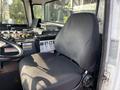 A black fabric driver seat inside a 2011 Autocar Xpeditor with various controls and buttons on the dashboard visible nearby