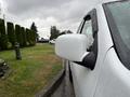 A 2011 Chevrolet Colorado with a white exterior and a side mirror covered in raindrops