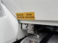 Close-up of a 2012 International 7400 truck's engine compartment showing two labeled heater connections for block and hydraulic heaters