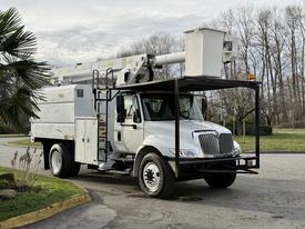A 2011 International 4300 bucket truck with a white exterior equipped with a raised platform and an extended arm for aerial work