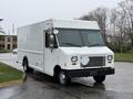 A 2012 Ford Econoline delivery truck with a white exterior and large front windows parked on a street