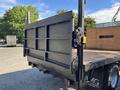 A 2014 RAM 5500 flatbed truck with a black rear gate featuring metal reinforcement and a wooden cargo area