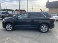 A black 2017 Ford Edge is parked with its side profile displayed showing sleek lines and alloy wheels