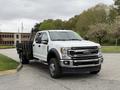 A white 2020 Ford F-550 truck with a black flatbed is parked at an angle, showcasing its front and side features