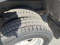 Two large, worn tires mounted on a 2012 Ford Econoline, positioned side by side with visible tread patterns and some dirt on the surface