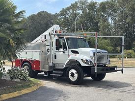 A 2012 International 7300 Workstar truck with a white exterior and red accents, equipped with a lift and various tools on the back