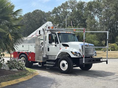 A 2012 International 7300 Workstar truck with a white exterior and red accents, equipped with a lift and various tools on the back