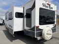 A 2013 Outdoor Wind River recreational vehicle with an extended slide-out and a spare tire mounted on the back featuring the brand name Wind River