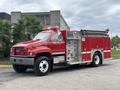 A red 2002 GMC C7500 fire truck with a silver water tank firefighting equipment and hoses on the side