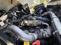 Close-up of the engine of a 2009 International 3000 CE showing various pipes wires and components including a metal manifold and a red cap