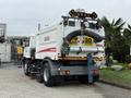 A 2009 UD Trucks UD 3300 street sweeper with a white and red body and a large vacuum hose attached at the rear