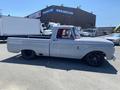 A gray 1962 Ford two-wheel drive pickup truck with a sleek design and black wheels parked at an industrial location.