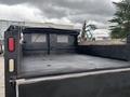 A black 2015 Mitsubishi Fuso FE160 truck bed with a flat surface and a metal rear tailgate featuring red and white lights on the back