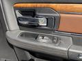 Close-up view of the door panel of a 2015 RAM 1500 featuring a chrome door handle a wood trim panel and buttons for window controls