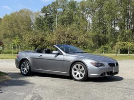 A silver 2004 BMW 6-Series convertible with a sleek design and a black interior parked on a street