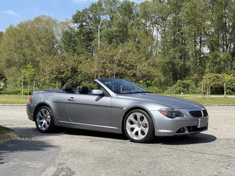 A silver 2004 BMW 6-Series convertible with a sleek design and a black interior parked on a street