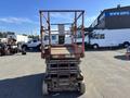 A 2010 SkyJack SJ scissor lift with a rusty metal platform and safety railing positioned on wheels