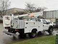 A 2006 Ford F-450 bucket truck with a raised aerial lift and utility box attached to the rear