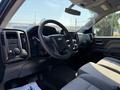 Interior of a 2017 Chevrolet Silverado 1500 featuring a black dashboard gray seats and steering wheel with controls and a gear shift on the center console