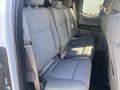 Interior view of the rear seating area of a 2017 Ford F-150 featuring gray fabric seats with seatbelts and ample legroom