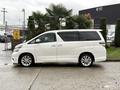 A white 2009 Toyota Vellfire parked with a sleek profile and large windows showcasing spacious seating inside