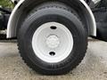 A close-up of a white truck tire mounted on a steel wheel featuring a tread pattern labeled Michelin XDE M/S with visible lug nuts and a black rubber exterior