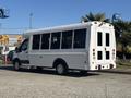 A 2017 Ford Transit-350 bus with a white exterior and large windows is parked, displaying a rear door design for easy entry and exit