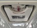 A ceiling-mounted emergency exit hatch with instructions in English and French on how to open it