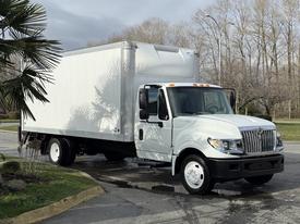 A 2014 International TerraStar box truck with a white exterior and a tall cargo area is parked with its front angled toward the viewer