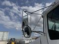 A 1996 Kenworth T800 truck with a prominent side mirror and shiny chrome details reflecting the sky