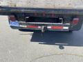A rear view of a 1996 GMC Top Kick truck featuring a wooden bed and a tow hitch with a safety pin attached