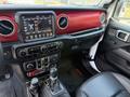 Interior view of a 2021 Jeep Wrangler showing the dashboard with touchscreen display and control knobs along with the gear shift and seating area