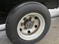 A close-up of a wheel from a 2012 Mitsubishi Fuso FE with a white rim and a black tire showing some rust on the wheel hub and bolts
