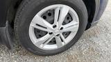 Close-up of a silver alloy wheel with a black tire on a 2019 Nissan Kicks showcasing a unique five-spoke design