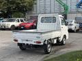 A white 2010 Daihatsu Hijet small truck with a flatbed and a cab in the rear view positioned prominently in the foreground