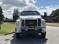 A white 2016 Ford F-750 truck with chrome details and large side mirrors parked with a clear view of the front headlights and grille