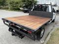 A white 2019 Ford F-350 SD truck with a flatbed made of wooden planks and black metal trim visible from the rear angle