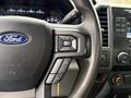 Close-up of the steering wheel of a 2019 Ford F-350 SD featuring audio control buttons and the Ford logo on the center console