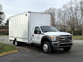 A 2012 Ford F-550 truck with a white box cargo area parked at an angle showcasing its dual rear wheels and front grille design