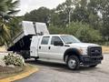 A 2014 Ford F-550 white pickup truck with a dump bed in an elevated position displaying its cargo capacity and heavy-duty design