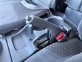 Close-up of the gear shift lever and surrounding console in a 2012 Isuzu NPR HD vehicle interior with gray fabric seating and cup holders