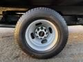 A close-up of a silver wheel with a black tire mounted on a 2015 GMC Savana showing the GMC logo in the center of the wheel