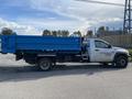 A white 2009 Dodge Ram 5500 truck with a blue dump bed attached on the back parked on a street