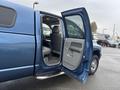 A blue 2006 Dodge Ram 2500 with an open rear door displaying a gray interior and seating area