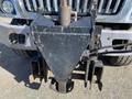 A black hitch attachment mounted on the front of a 2014 International 7400 truck with a triangular shape and various metal components visible