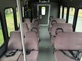 Interior view of a 2014 Ford E-350 showing multiple cloth-covered seats arranged in rows with seat belts visible